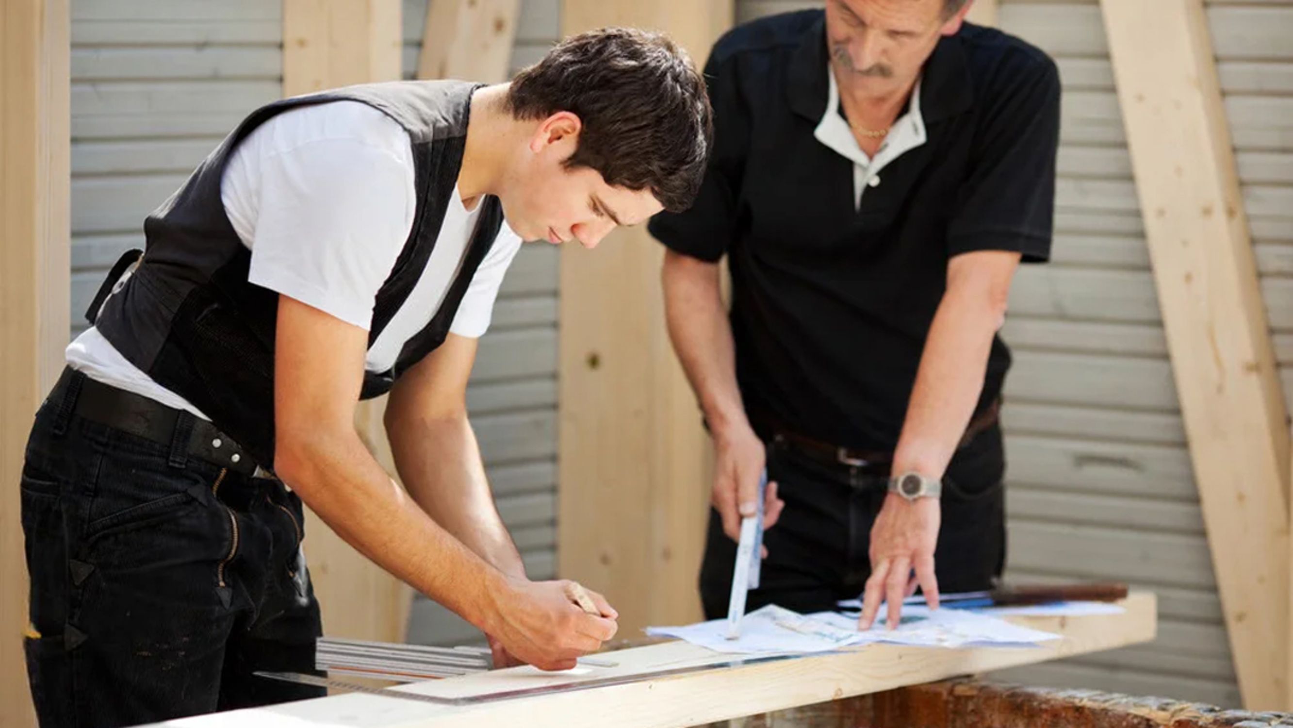 Zimmererlehrling mit Meister bei der Arbeit